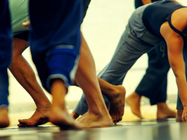 Image is of human feet in motion and set in place, some humans are bent over with hands on floor.